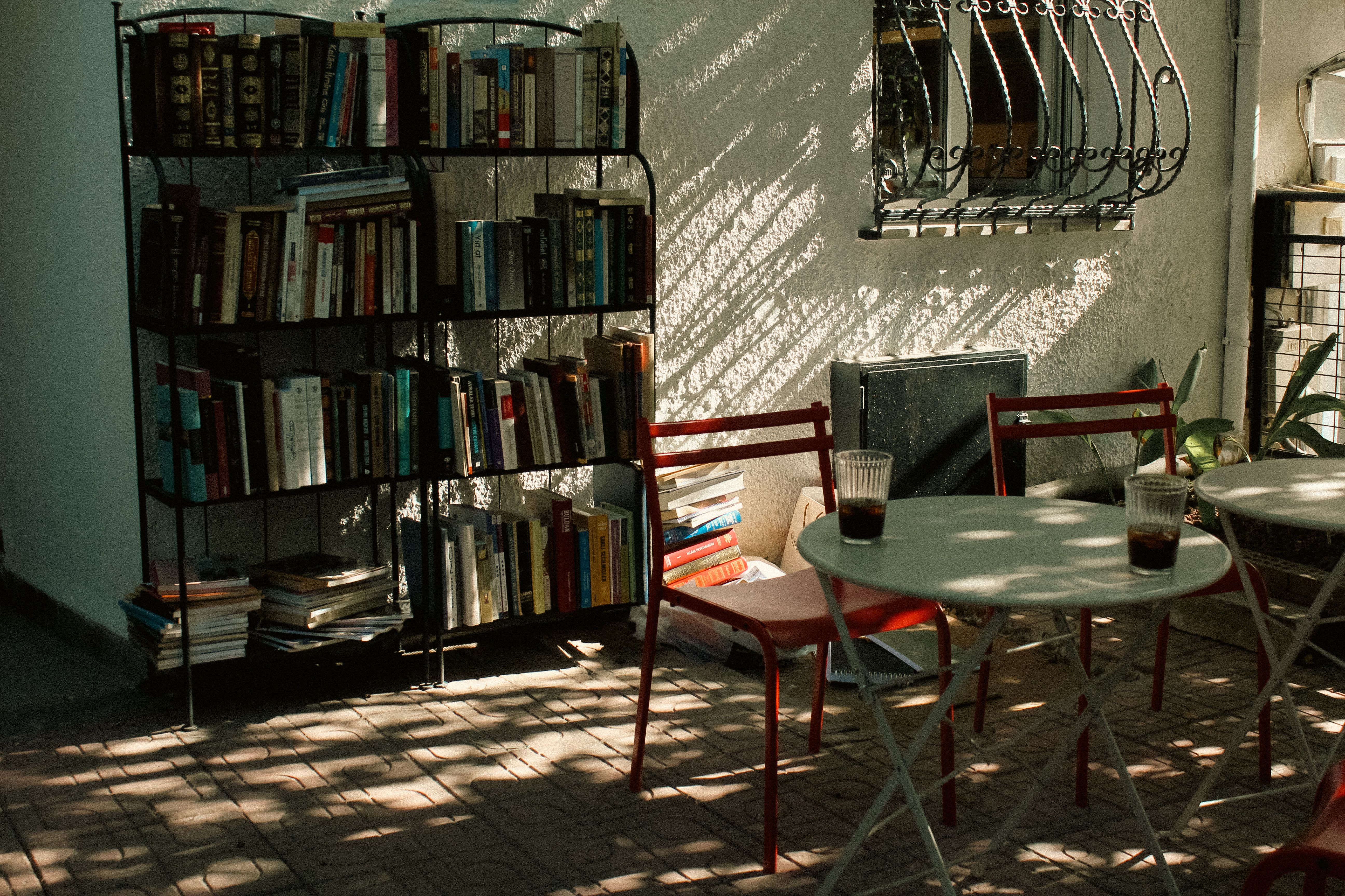 Serene outdoor reading area with bookshelf, chairs, and tables in warm lighting